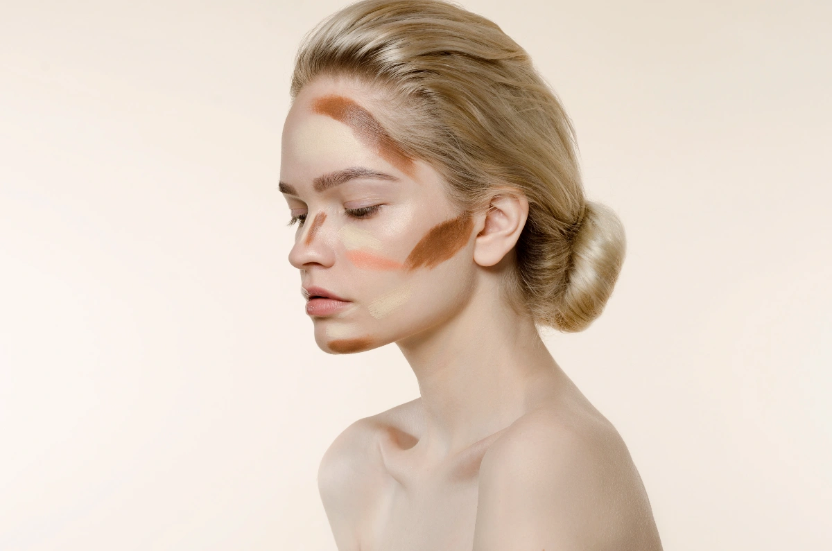 Visage d’une femme avec plusieurs pigments prêts à être appliqués.